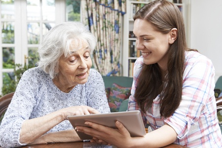 46634489 - teenage granddaughter showing grandmother how to use digital tablet