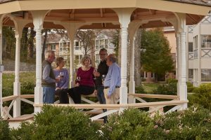 Image of 5 Meth-Wick residents enjoying an outdoor gazebo on Meth-Wick's expansive campus. 